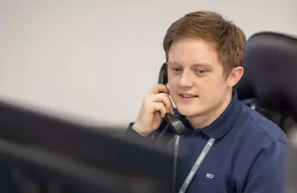 Man in office speaking on the telephone wearing a blue jumper