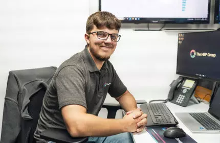 Young man looking at camera smiling behind computer desk
