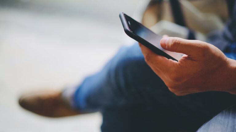 man-waring-jeans-using-smartphone-with-left-hand-copy-space-left-min